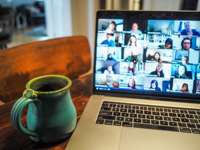 A laptop screen showing many participants in a video call