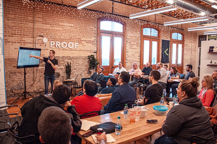 A speaker addressing workshop participants seated around a long table